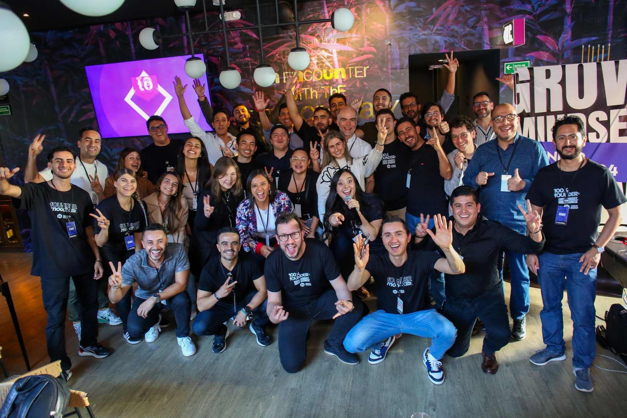 Grupo celebrando con las manos arriba en un evento de founders.